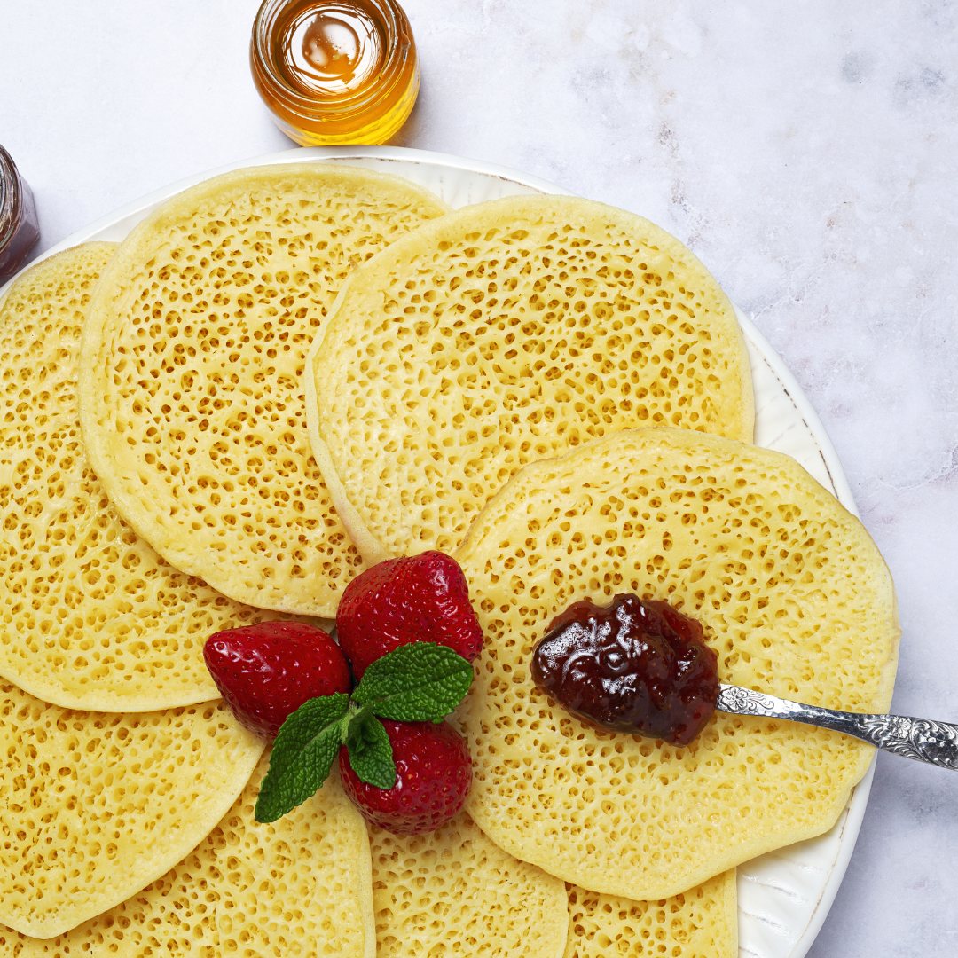 Baghrirs aux mille trous servis avec des fraises et de la confiture